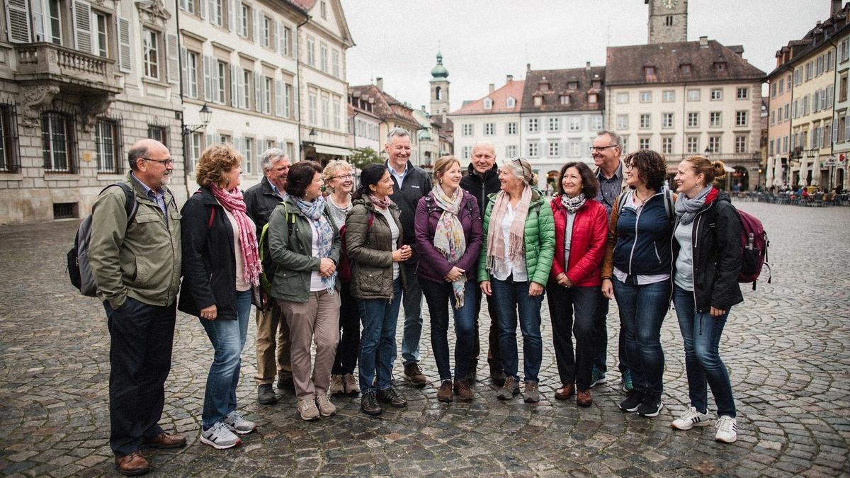 Group of sixteen travelers standing with their local guide on a small group tour in central Europe